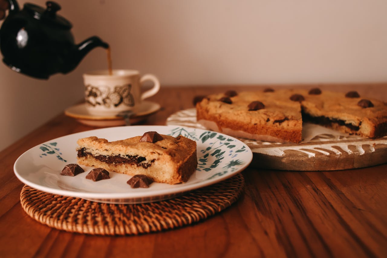 why-choose-us A slice of chocolate chip cake served with tea in a cozy indoor setting, perfect for warm moments.